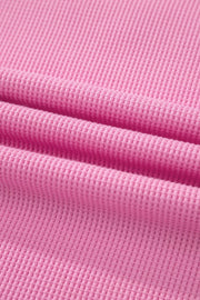Pink waffle knit polyester t-shirt with a pocket detail and textured fabric.