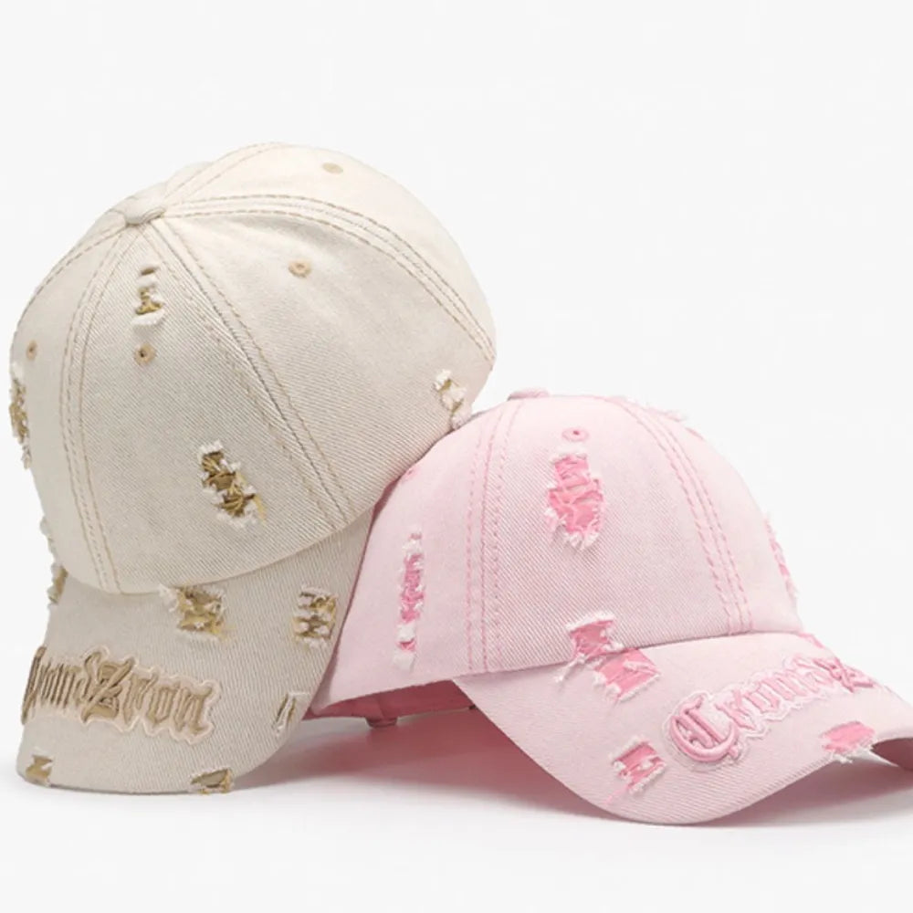 Distressed baseball cap in blush pink with embroidered text and frayed details.