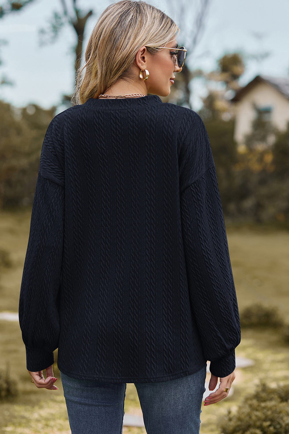 Dark blue cable knit v-neck pullover sweater with textured fabric and long sleeves.