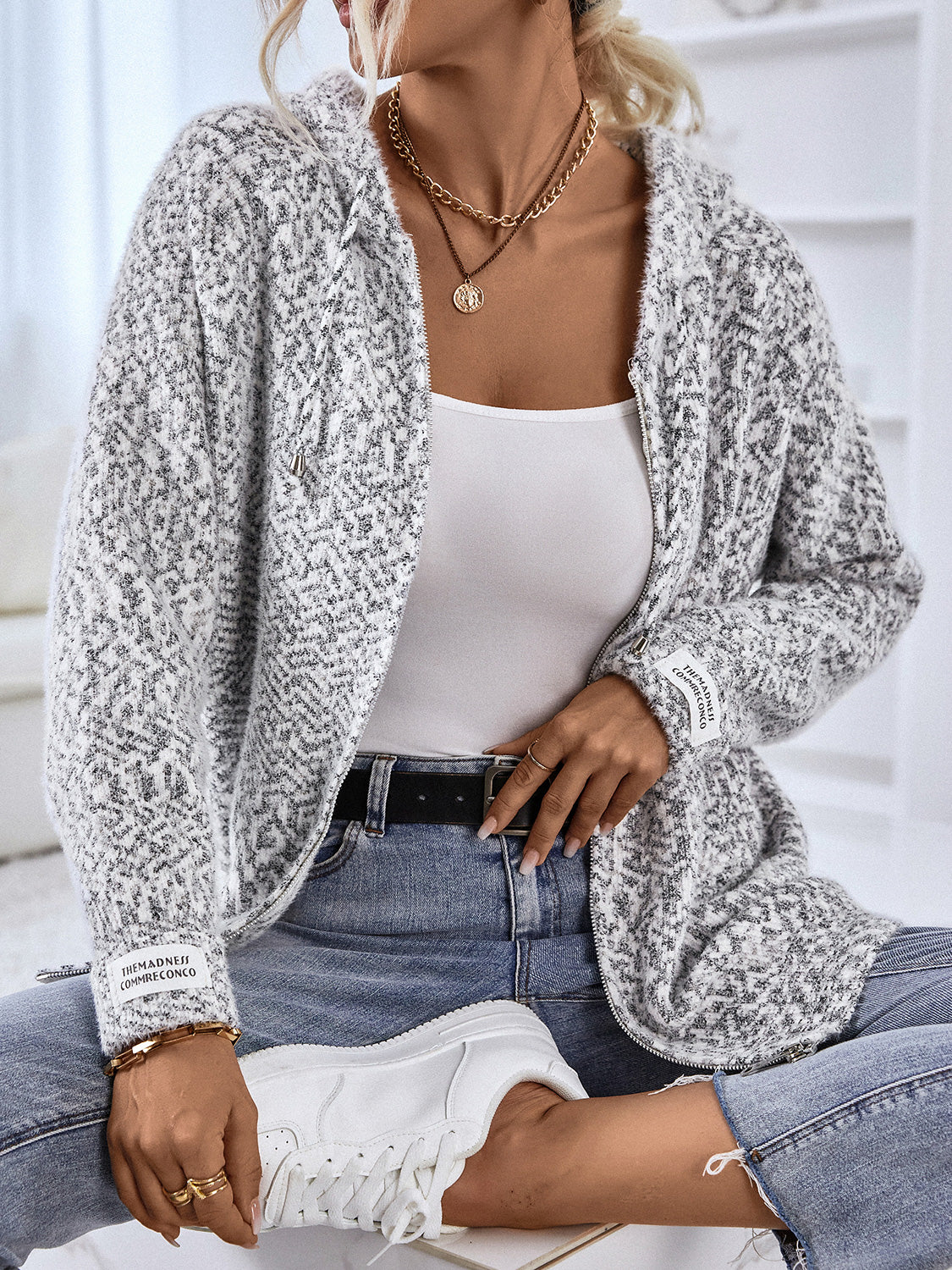 Textured knit zip-up cardigan in charcoal with a subtle geometric pattern and logo detail on the sleeve.