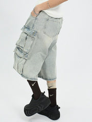 Men's light wash denim cargo capris with multiple pleated pockets and a relaxed fit.