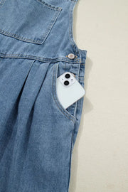 Denim jumpsuit with wide legs, pleats, and a pocket holding a smartphone.