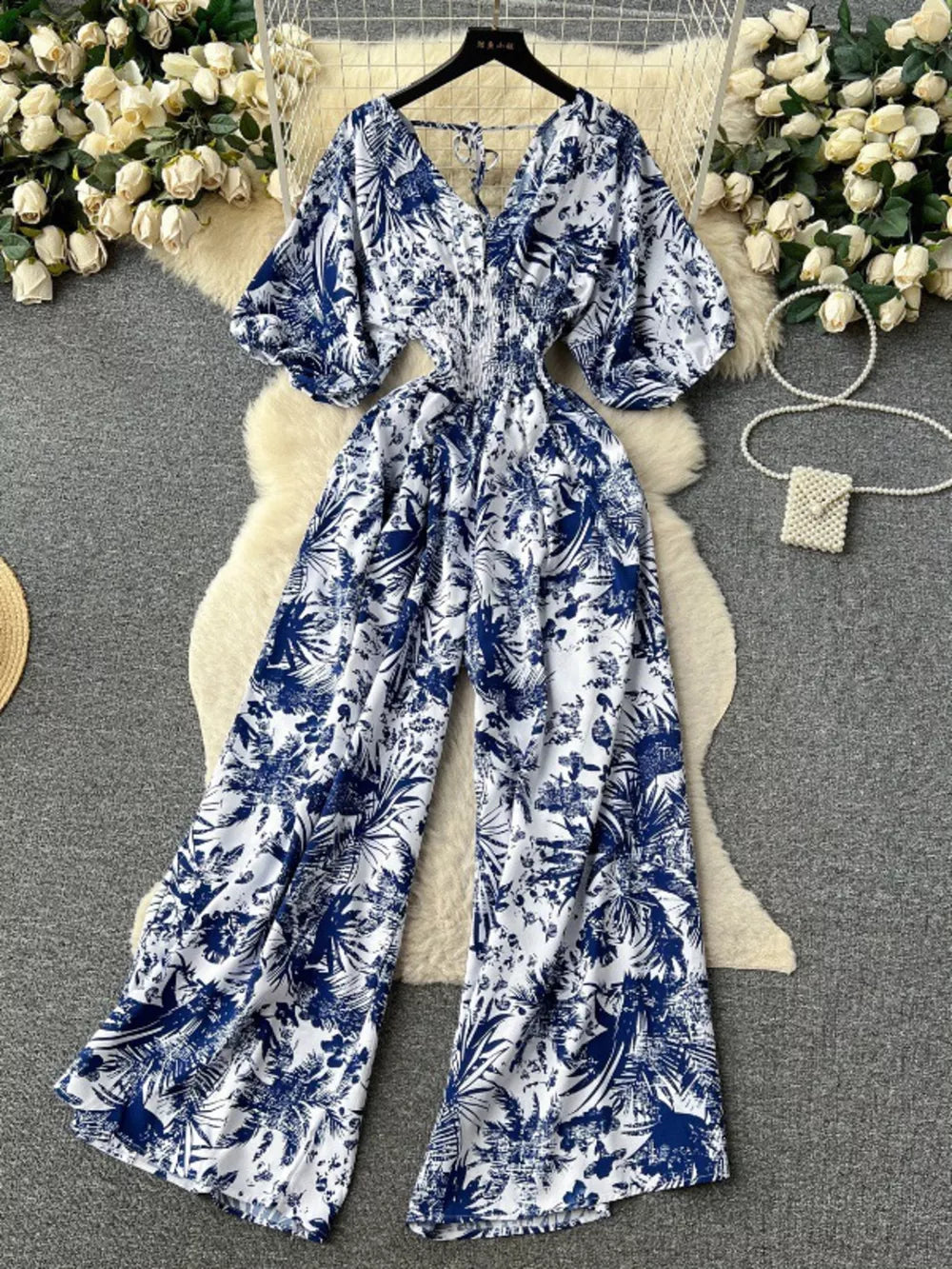 Tropical print smocked wide-leg romper in Dark Blue with V-neck and tie back.