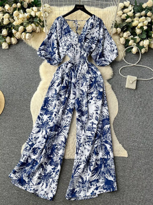 Tropical print smocked wide-leg romper in Dark Blue with V-neck and tie back.