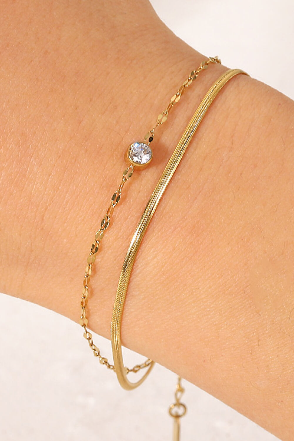 Gold double-strand bracelet with pavé charm and flat snake chain.