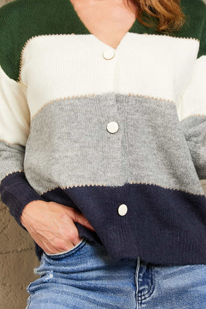 Colorblock acrylic cardigan with metallic trim in green, white, grey, and navy with white buttons.