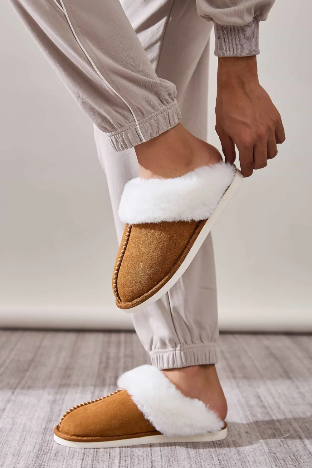 Caramel suede house slides with white shearling trim and contrast stitching.