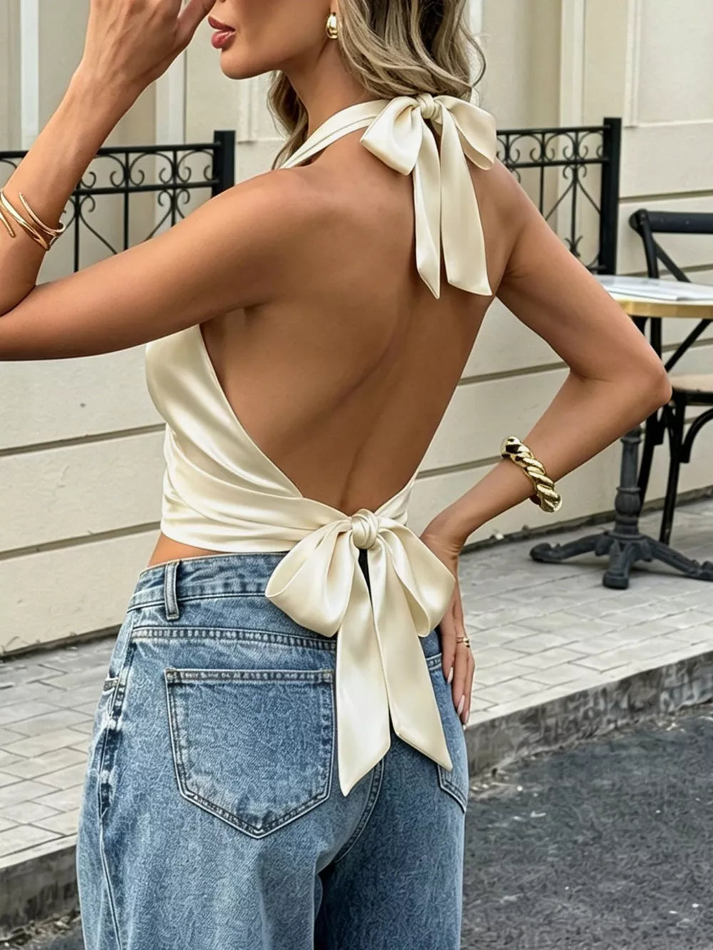 Satin halter tank top in cream with gathered neckline and back bow detail.