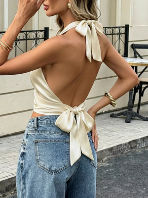 Satin halter tank top in cream with gathered neckline and back bow detail.