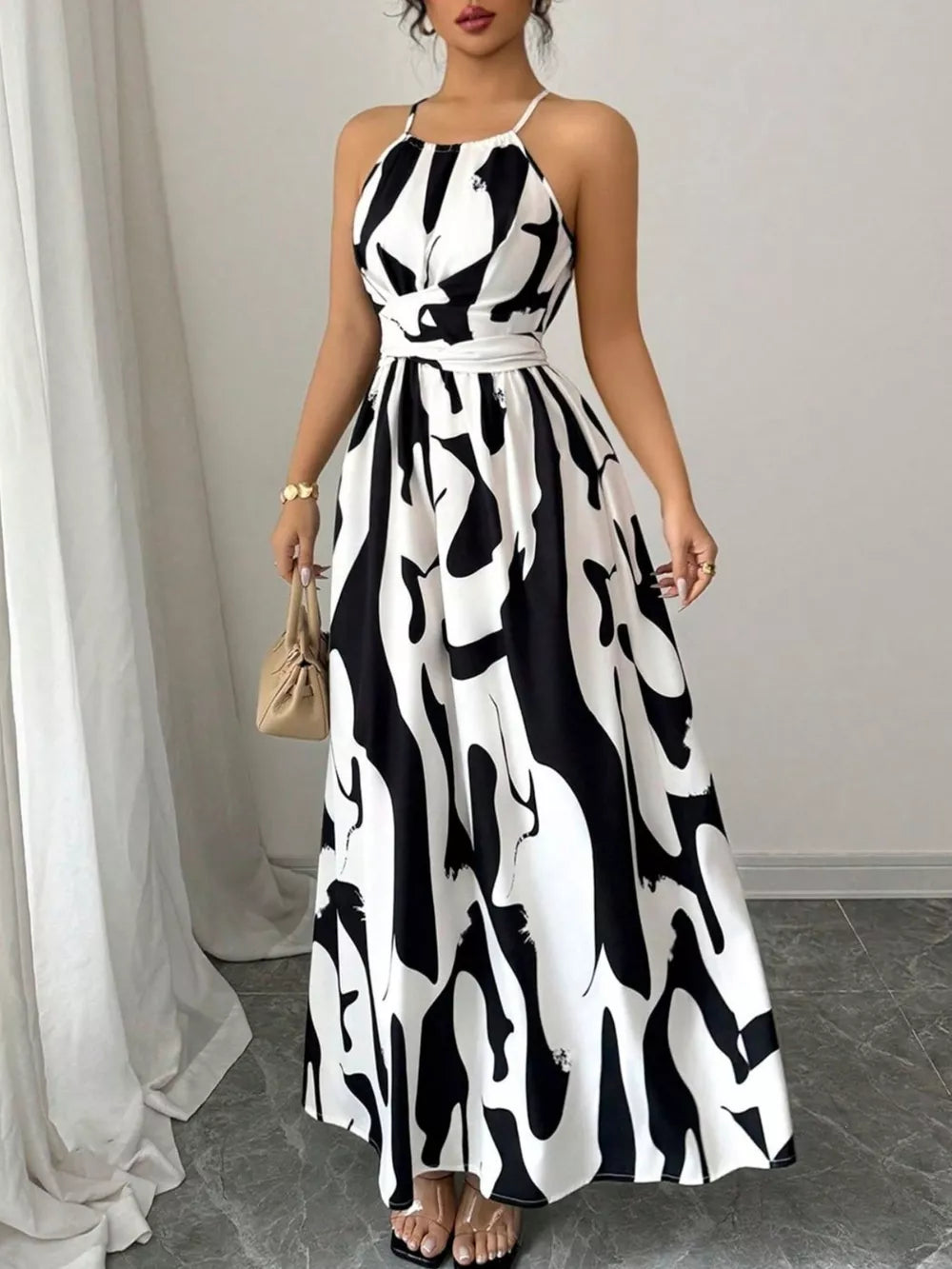 Maxi dress with halter neck, abstract print, and tie waist in black and white.