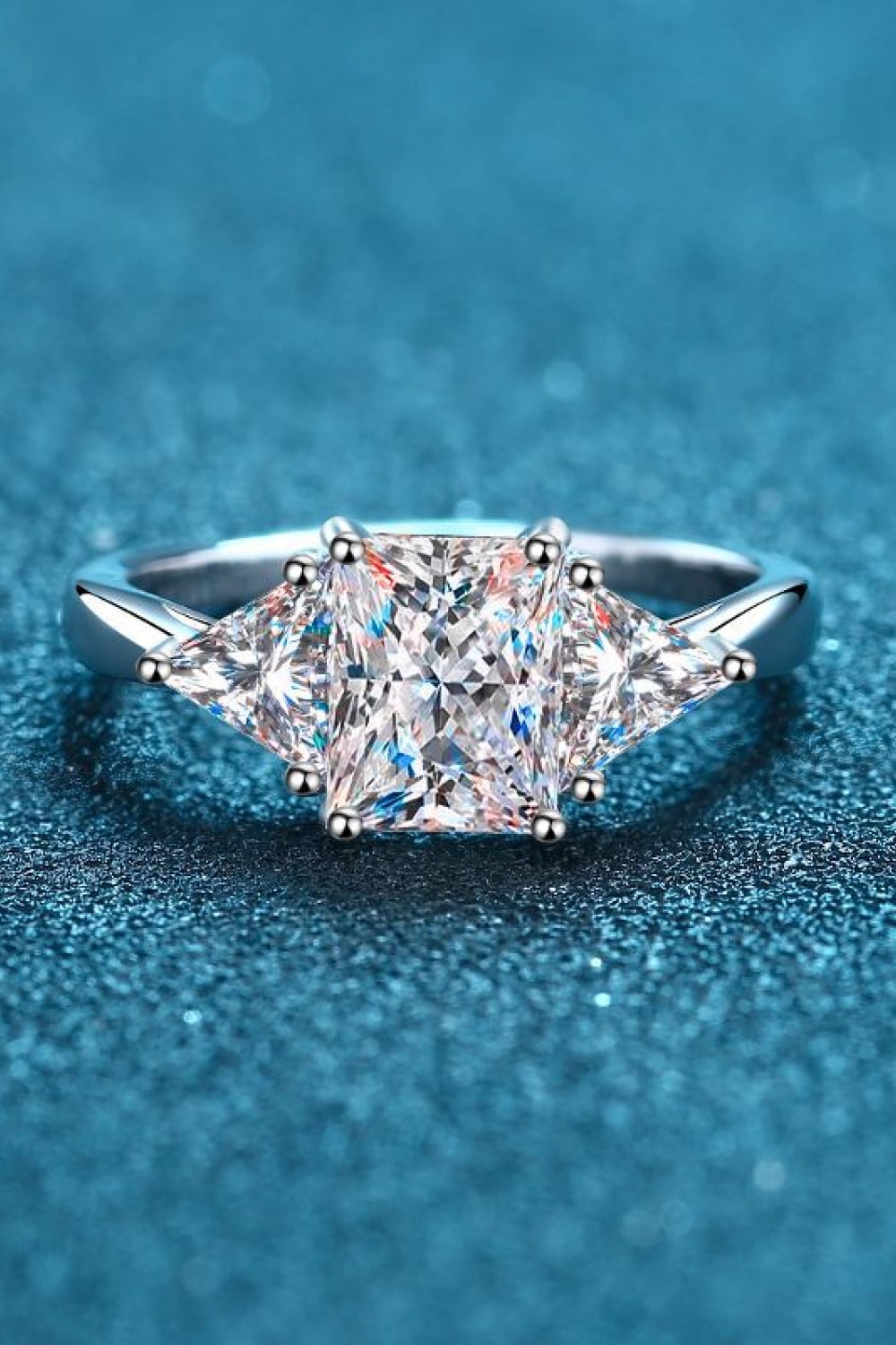 Silver trilogy ring with a large princess-cut center stone and two triangle-cut side stones.