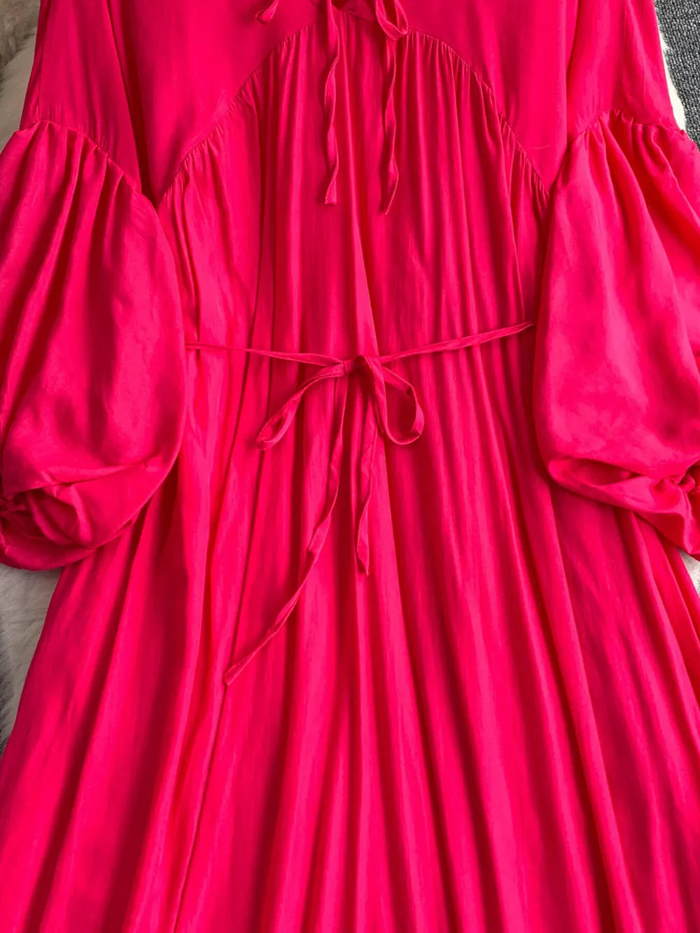 Fuchsia pink polyester maxi dress with balloon sleeves, tie neckline, and cinched waist.