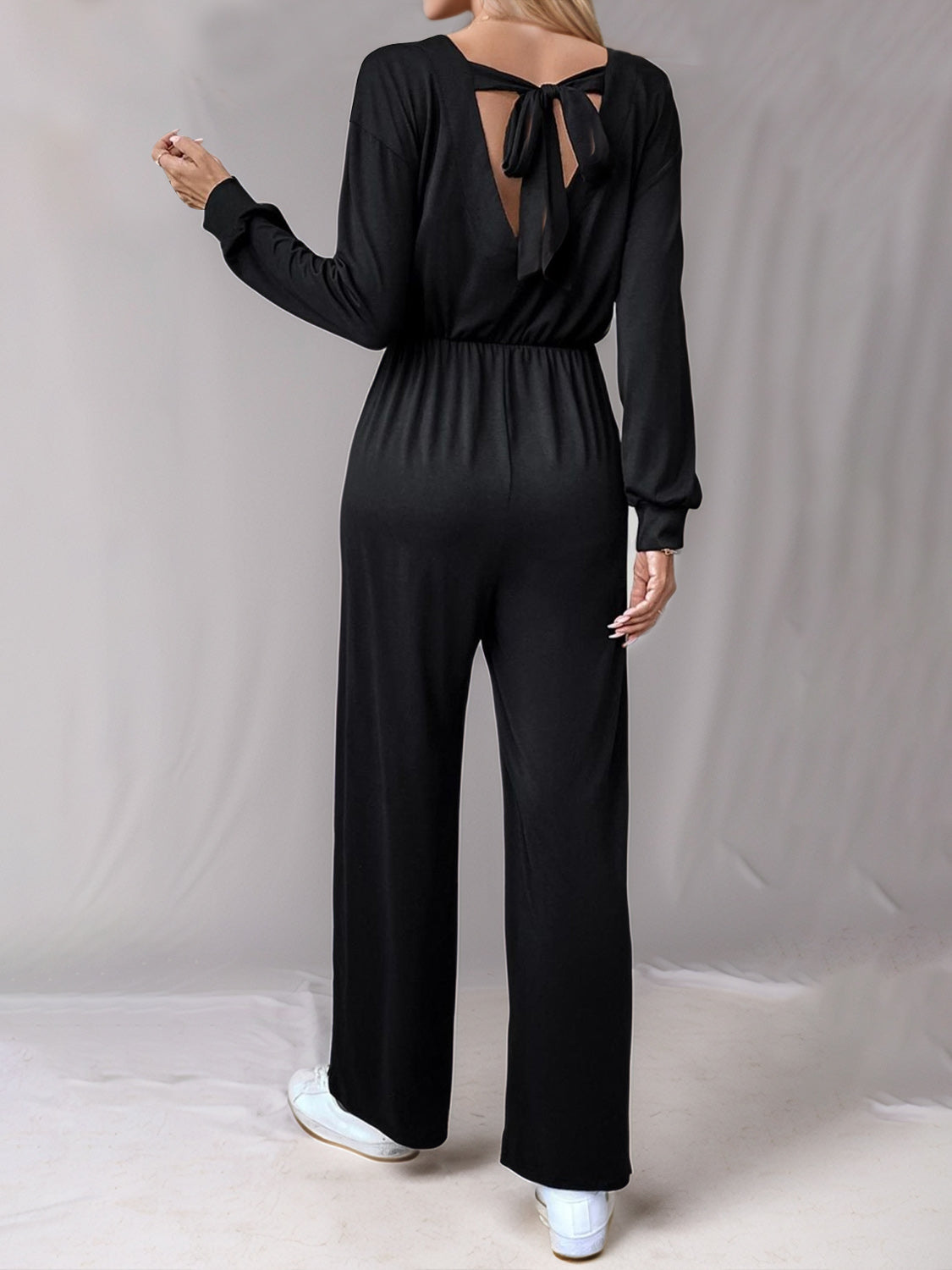 Black wide leg jumpsuit with long sleeves and a back tie detail.