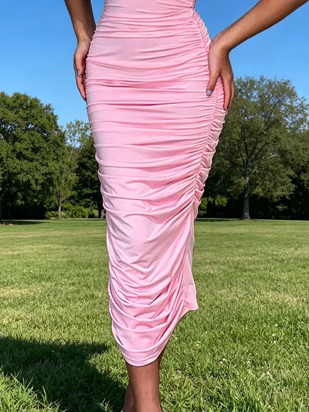 Pink ruched bodycon midi dress with floral appliqué detail.