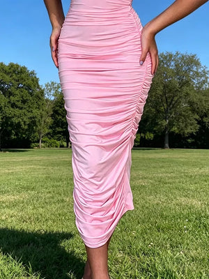 Pink ruched bodycon midi dress with floral appliqué detail.