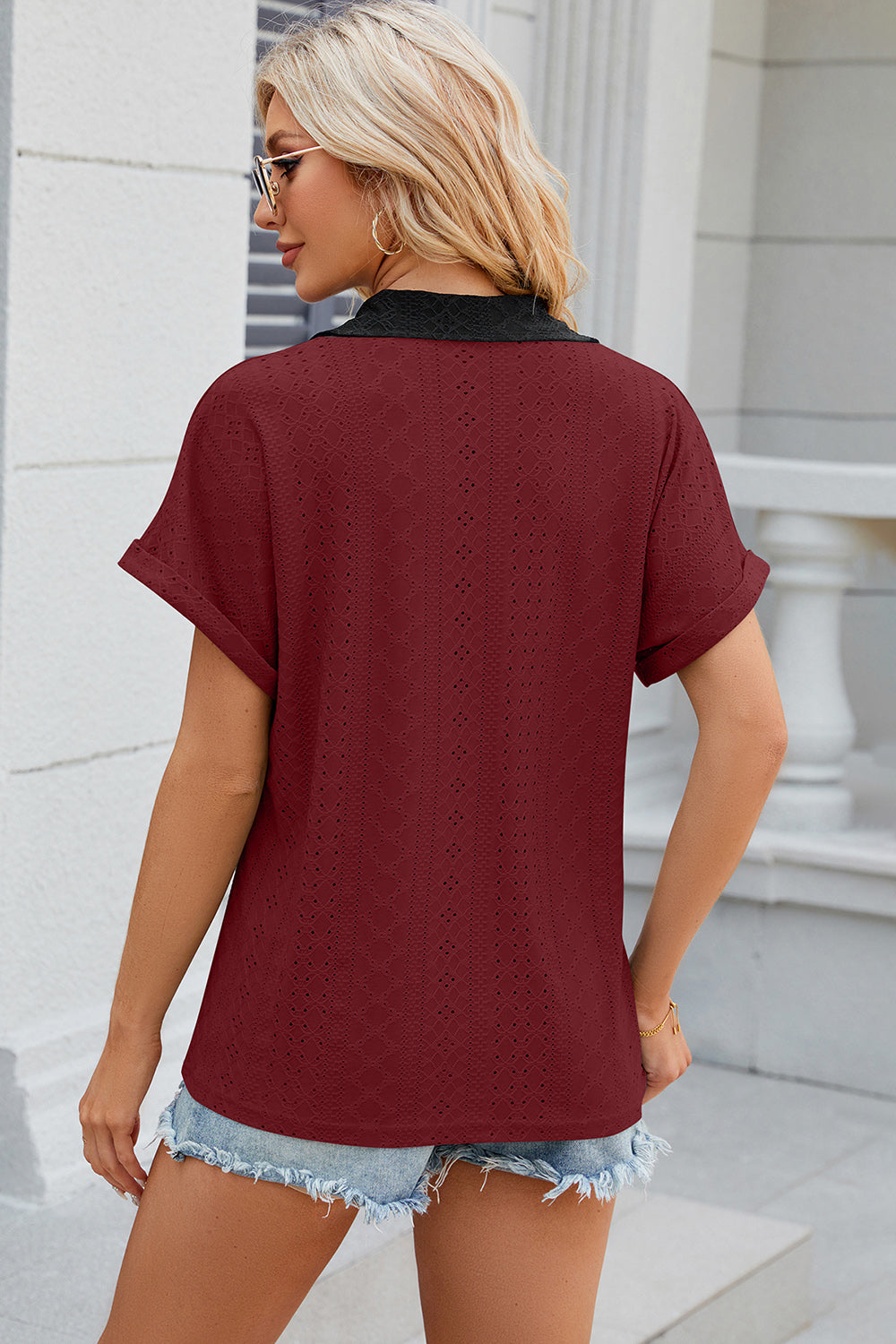 Burgundy perforated polo top with black lace collar and cuffed short sleeves.