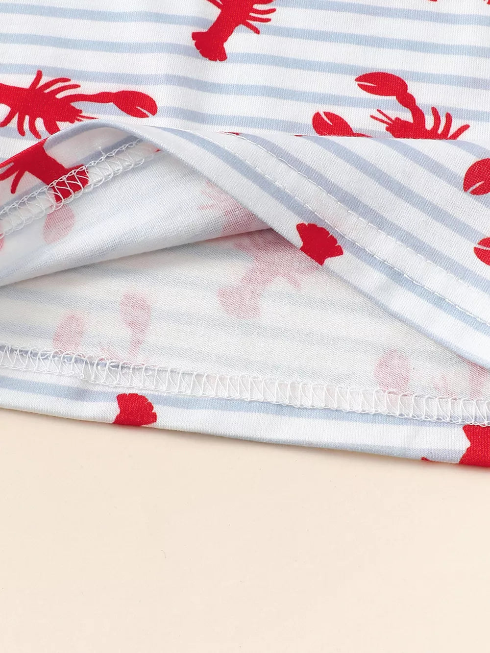 Baby set with red lobster print on blue and white stripes, showing garment seams.