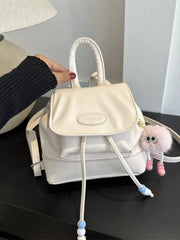 White mini leather drawstring backpack with beaded detail and fluffy charm