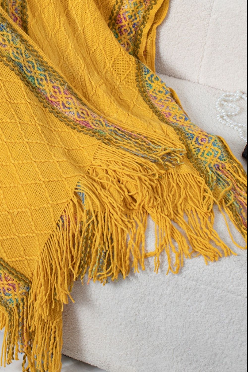 Mustard knit wrap coat with diamond pattern, embroidered trim, and fringe details.