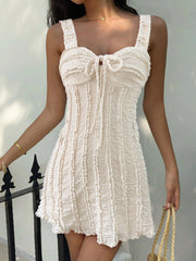 Beige ruched sweetheart neck mini dress with tie detail and textured fabric.