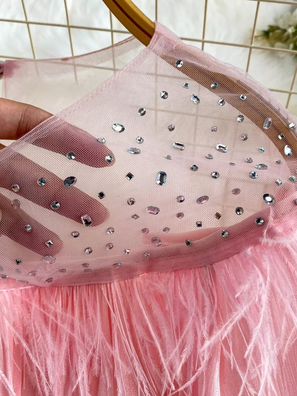 Pink sheer mesh blouse with scattered rhinestones and feather trim detail.