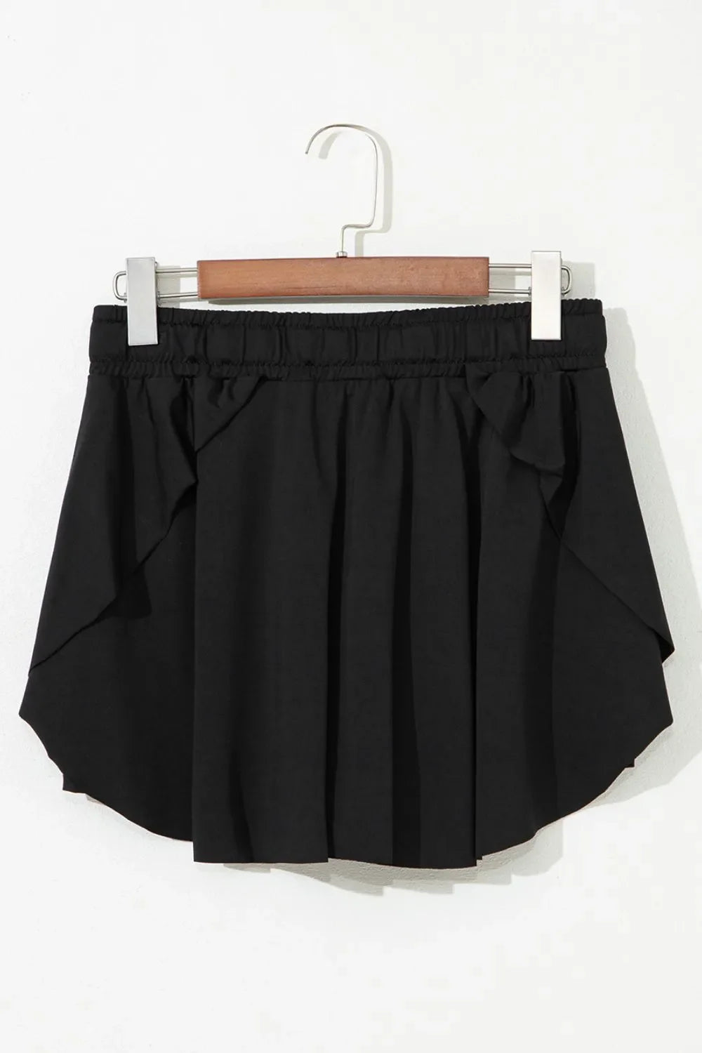 Black flared skort with tie waist and ruffled hem detail.
