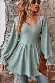 Sage textured blouse with V-neck, empire waist, and shirred sleeves.