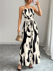 Chic halter neck maxi dress in white with abstract black print, featuring a belted waist.