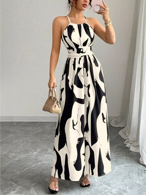 Chic halter neck maxi dress in white with abstract black print, featuring a belted waist.