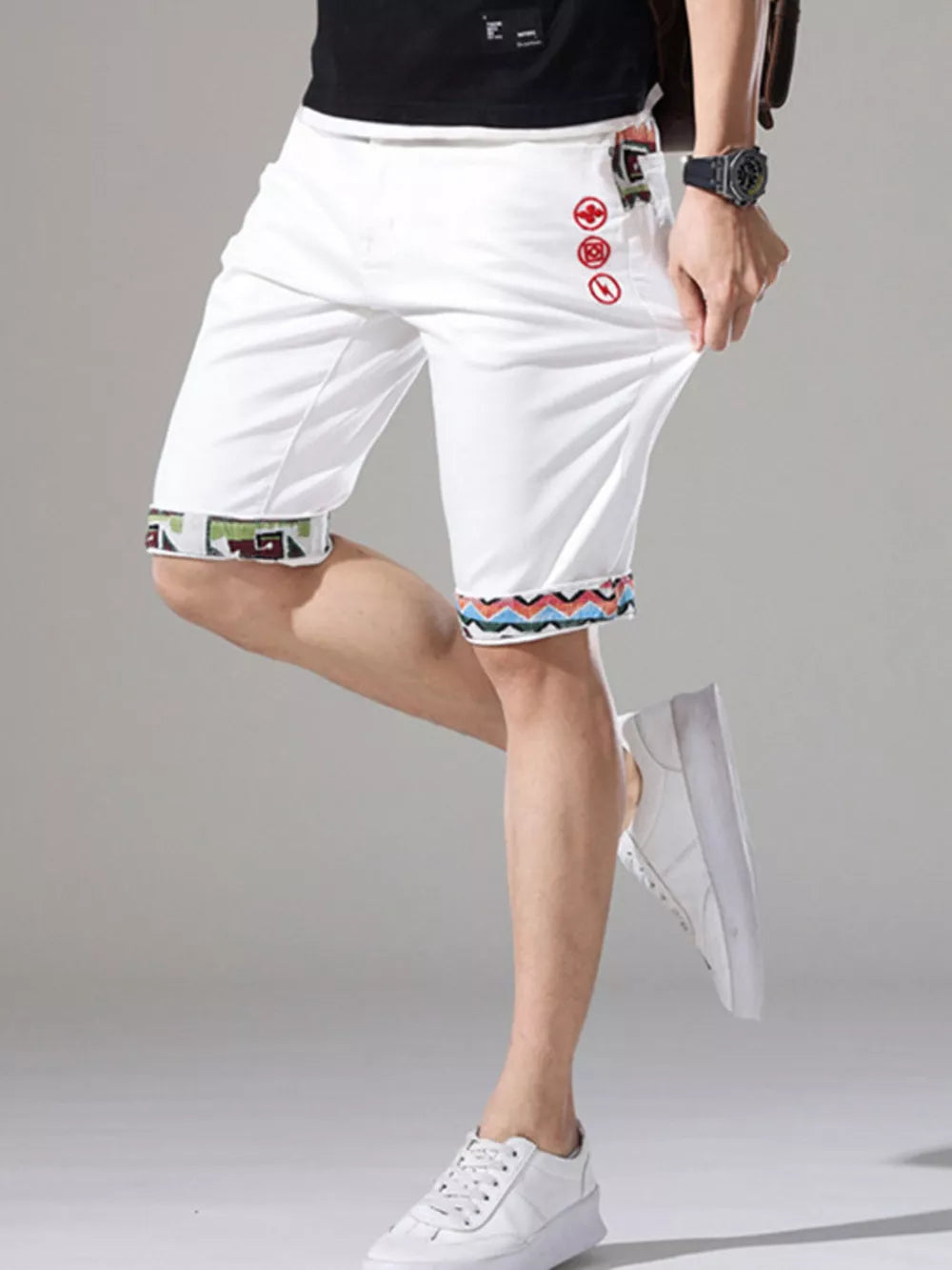 Men's white denim shorts with decorative rolled cuffs and red embroidered details.