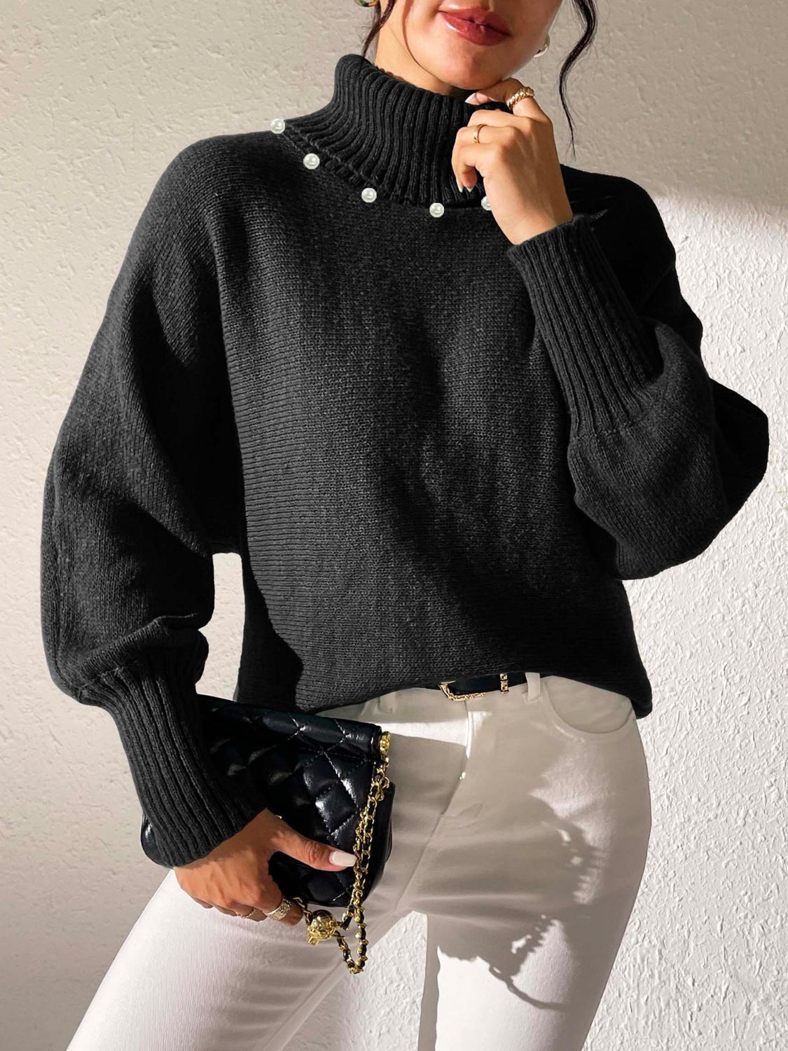 Black knit sweater with pearl details on the neckline and dolman sleeves.