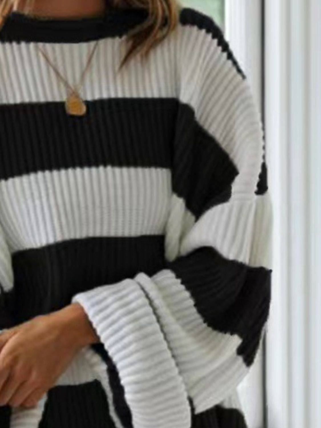 Black and white striped oversized knit sweater with ribbed texture and wide sleeves.
