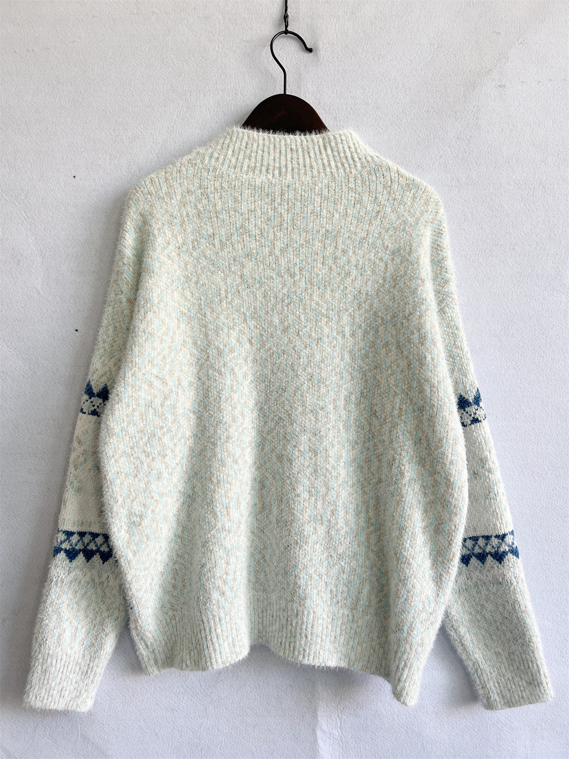 Geometric knit mockneck pullover in Eggshell with blue diamond pattern on sleeves.
