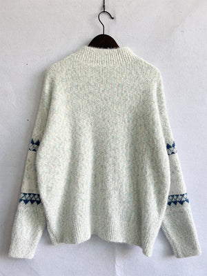 Geometric knit mockneck pullover in Eggshell with blue diamond pattern on sleeves.