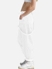 White denim overalls with relaxed fit and crisscross straps, styled with white sneakers.
