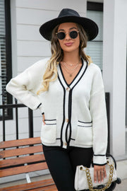 White acrylic cardigan with black trim and pockets, V-neck, button front, long sleeves.