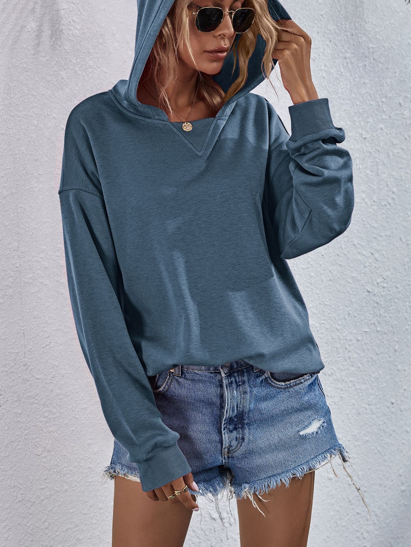 Dusty Blue boxy hooded sweatshirt with split V-neck and cuffed sleeves.
