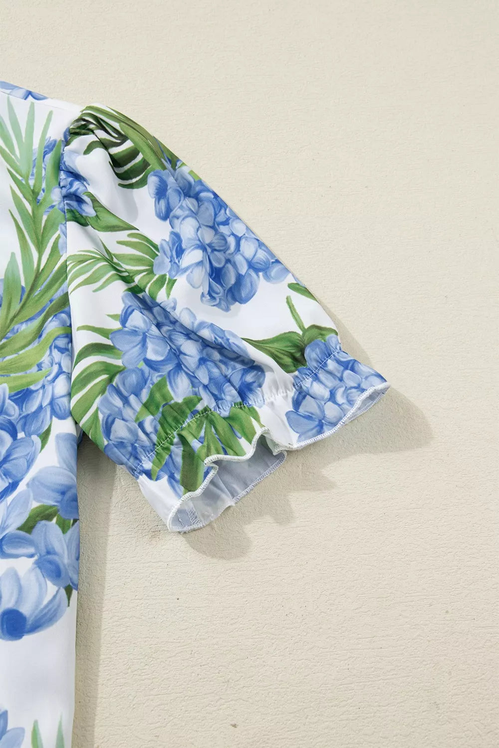 Tropical floral blouse with blue hydrangea print and ruffled short sleeves.