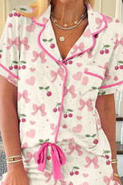Ivory pajama set with pink bows and cherries pattern, short sleeves, button front, piped trim