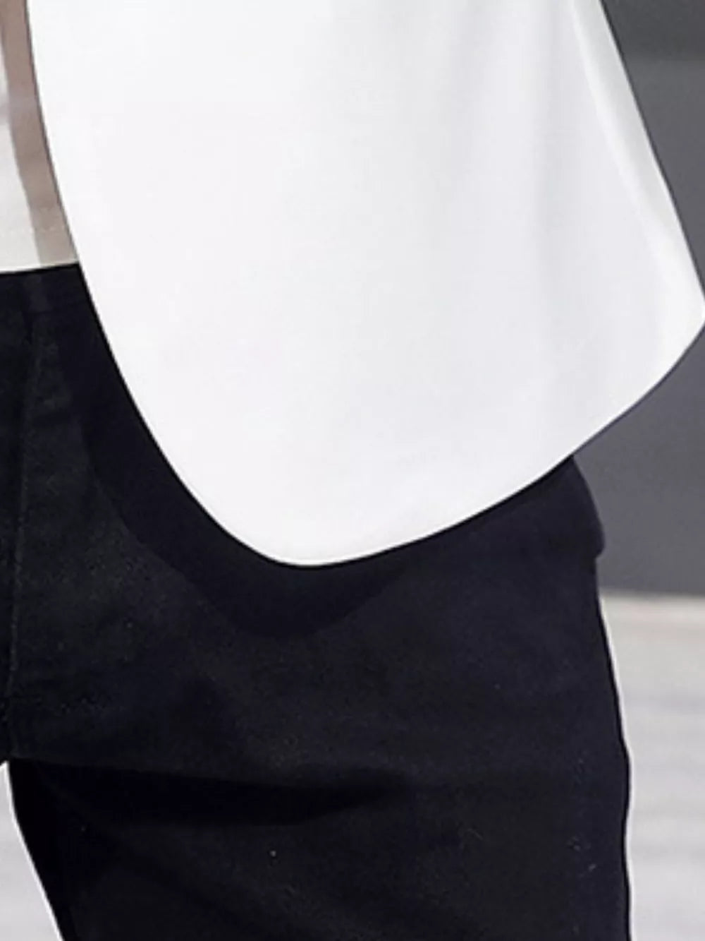 White double-breasted blazer with black trim detail over black pants