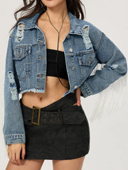 Distressed denim trucker jacket in medium wash with fringe trim and frayed hem.