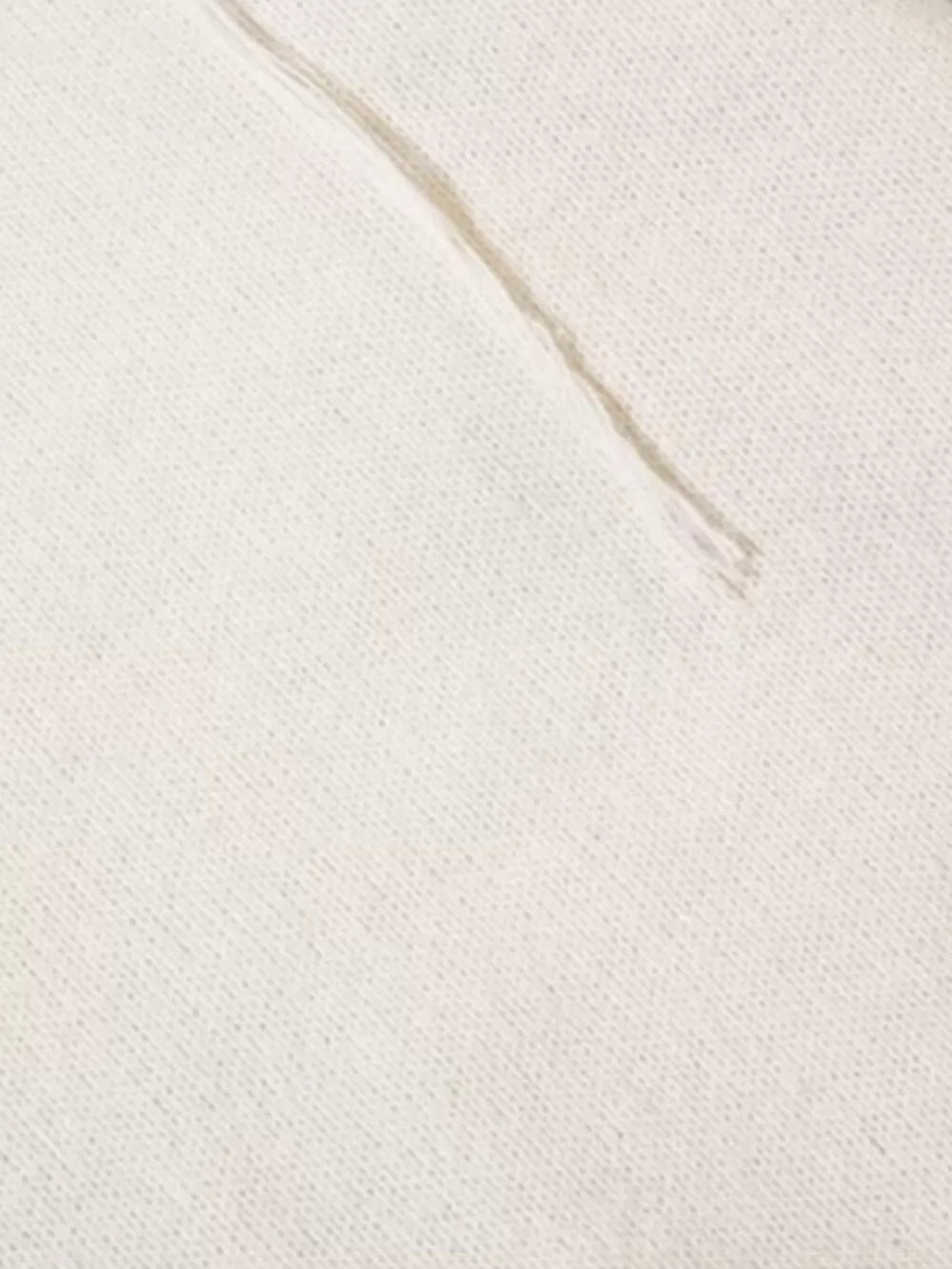 Cream knit sweater detail with textured stitching and abstract pattern.