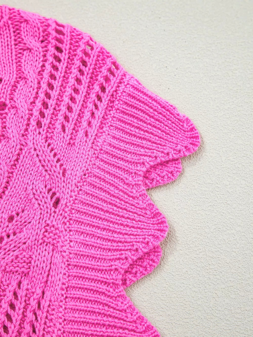 Chic openwork knit sweater vest in bright pink cotton with cable knit details and scalloped edge.