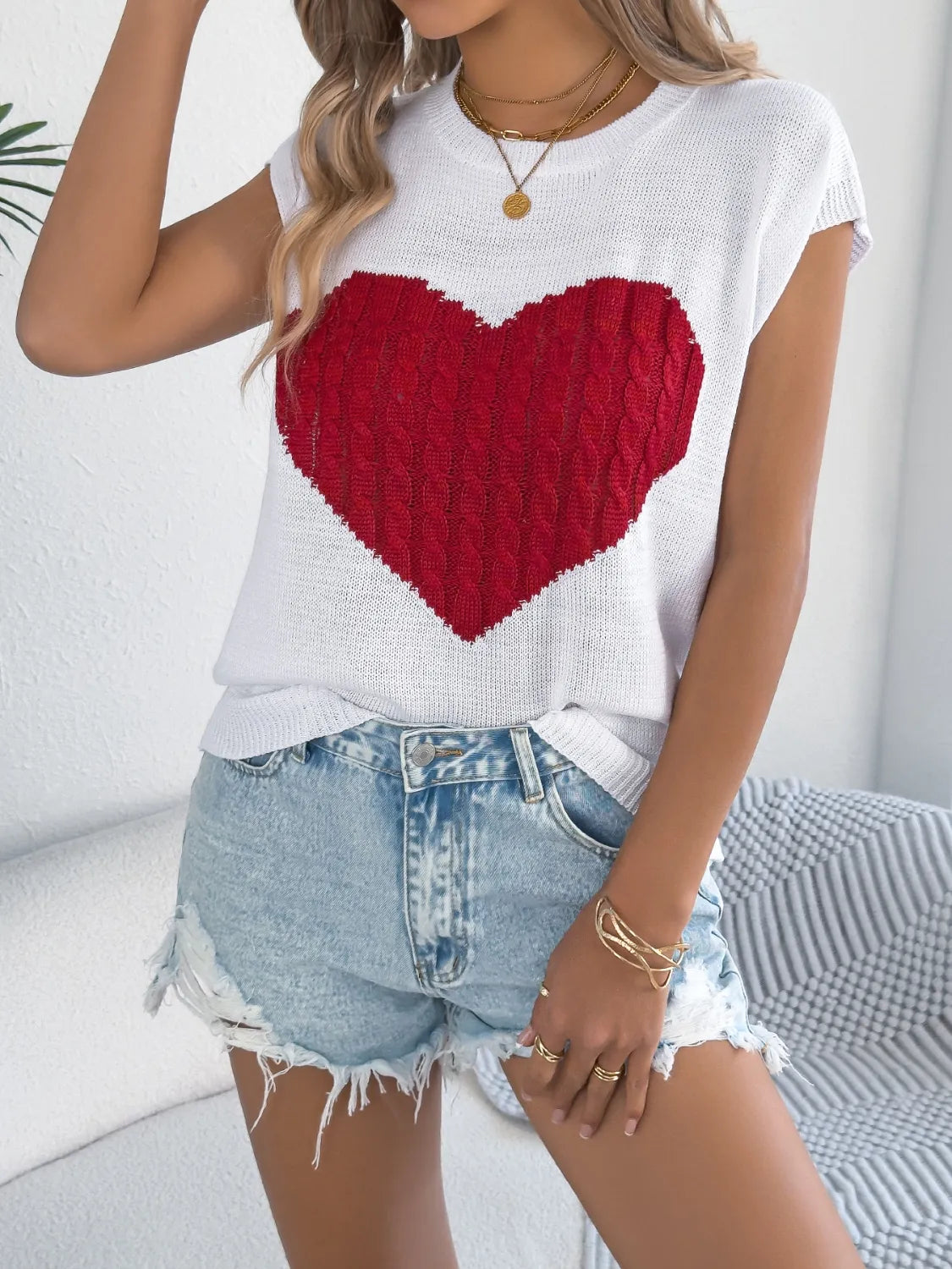 White cable knit sweater vest with a red cable knit heart graphic.