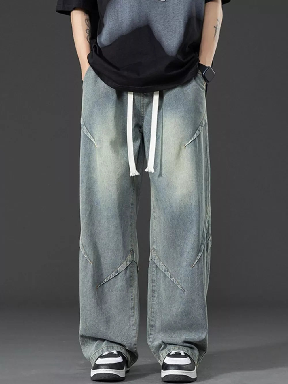 Men's vintage-inspired oversized blue denim jeans with white drawstring and unique seam details.