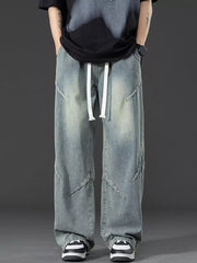 Men's vintage-inspired oversized blue denim jeans with white drawstring and unique seam details.