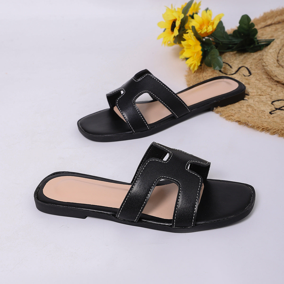 Black H-strap open-toe sandals with contrast stitching and a flat sole.
