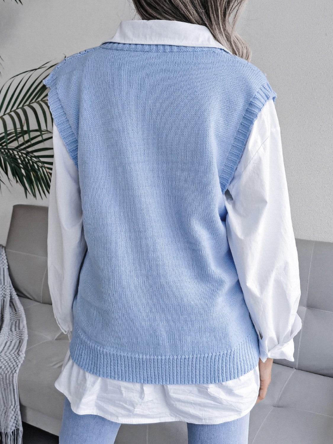 Light blue openwork cable knit vest with ribbed trim, layered over a white shirt.
