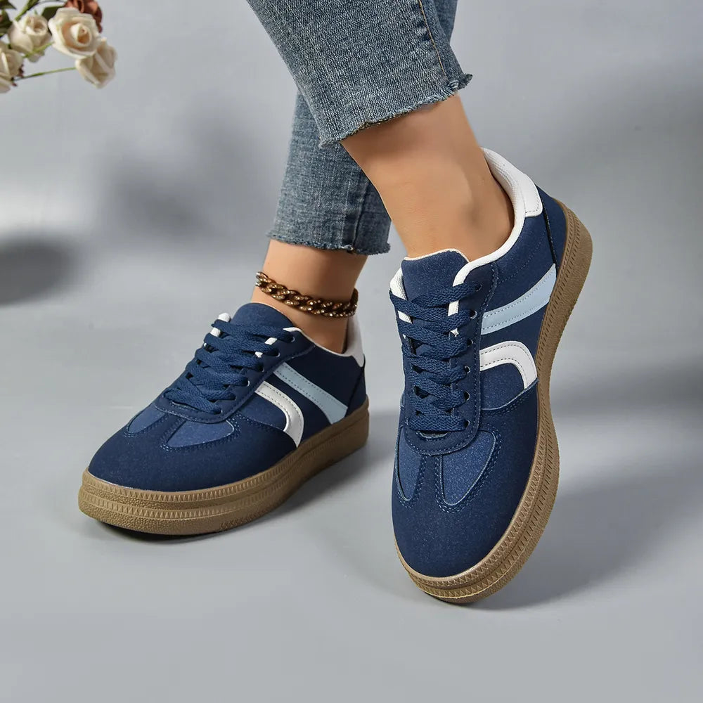 Navy suede platform sneakers with curved white and light blue stripes and a gum sole.