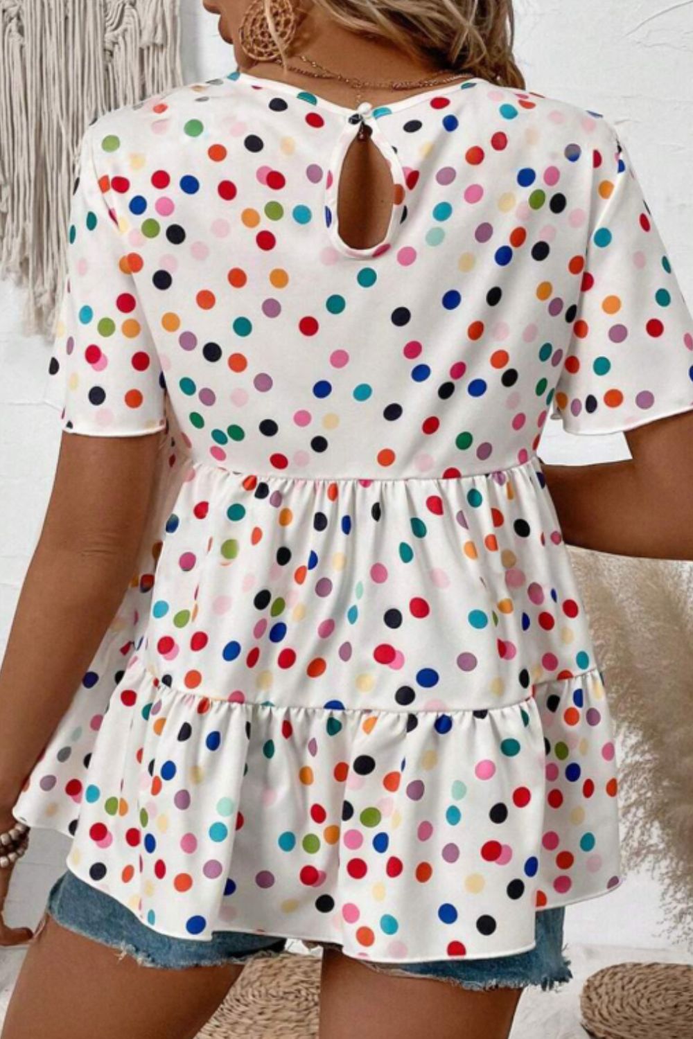 White tiered babydoll blouse with colorful polka dots and flutter sleeves.